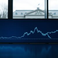 Digital display showing a steady USD/CHF currency chart with Swiss National Bank building in the background.