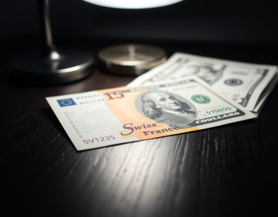 Swiss Franc and US Dollar banknotes on a desk, representing currency exchange rate movements.