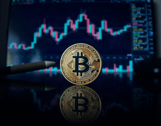 Bitcoin coin on reflective surface with trading charts in background