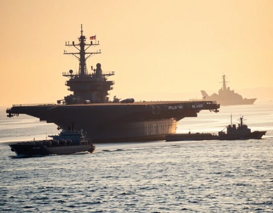 US Navy aircraft carrier patrolling the Strait of Hormuz at dawn