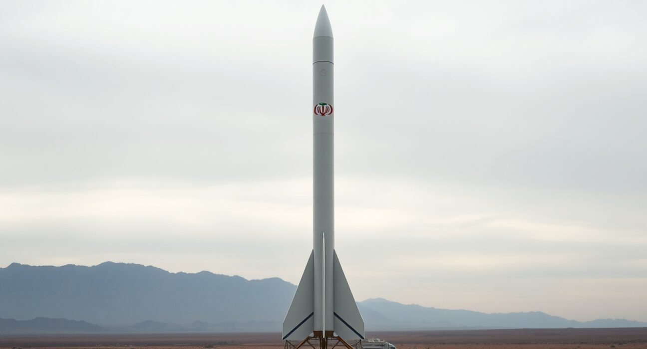 Iranian ballistic missile on launch pad under overcast sky, representing Trump's threat to destroy remaining missiles if nuclear deal fails.