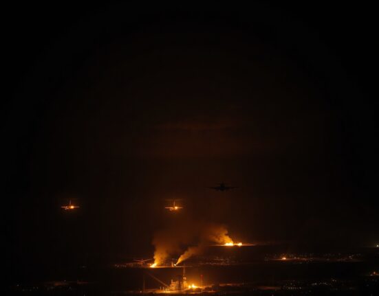 Night scene over Middle East with military aircraft and burning infrastructure on horizon