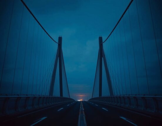 Empty bridge at dusk with orange glow on horizon, symbolizing threat of military strikes.