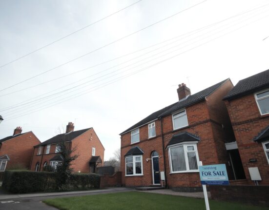 UK residential street with terraced houses and a for-sale sign, illustrating flat house price data for July