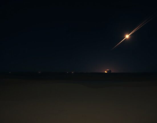 Nighttime airstrike in desert region with explosions on the horizon
