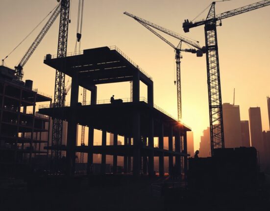 Construction workers on a steel framework site in a US city, with cranes in background