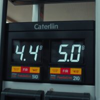 Close-up of a gas station fuel pump display showing a high price per gallon, symbolizing inflation driven by oil prices.