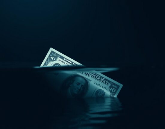 US dollar bill partially submerged in water representing downside risk and uncertainty in currency markets.