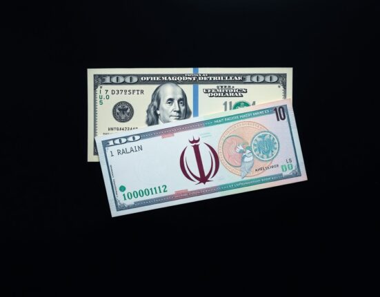 US dollar and Iranian rial banknotes on a dark surface representing forex market reaction to peace hopes