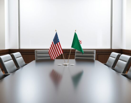 US and Iranian flags on a conference table symbolizing diplomatic negotiations