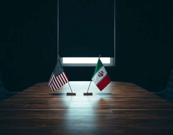 Empty diplomatic meeting room with US and Iranian flags, symbolizing ongoing negotiations.