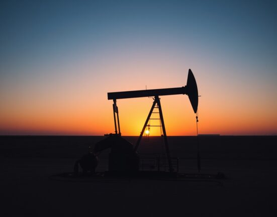 Oil drilling rig on a plain at sunset, representing US energy production activity.