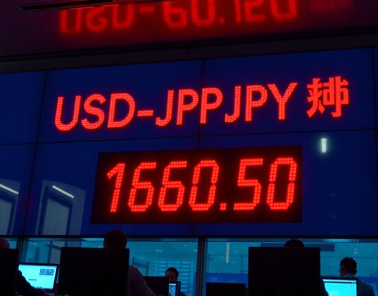 Digital currency board showing USD/JPY exchange rate at 160.50 on a Tokyo trading floor