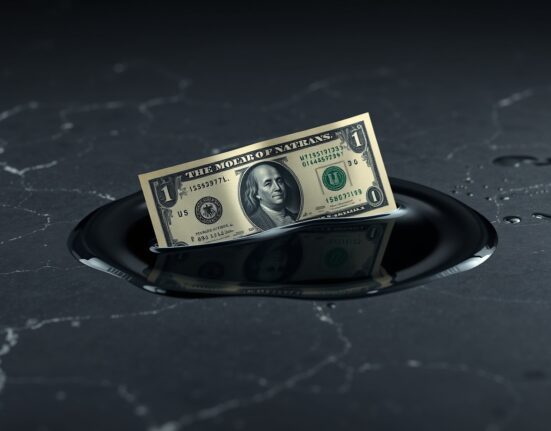 U.S. dollar bill partially submerged in crude oil representing energy and currency markets