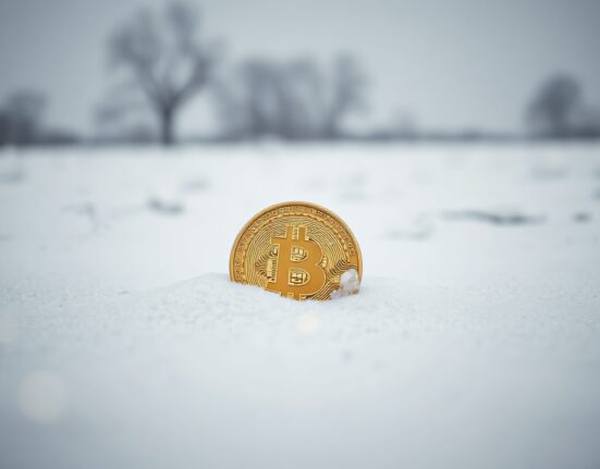 Bitcoin coin partially buried in snow, symbolizing a delayed market bottom in a bear market.