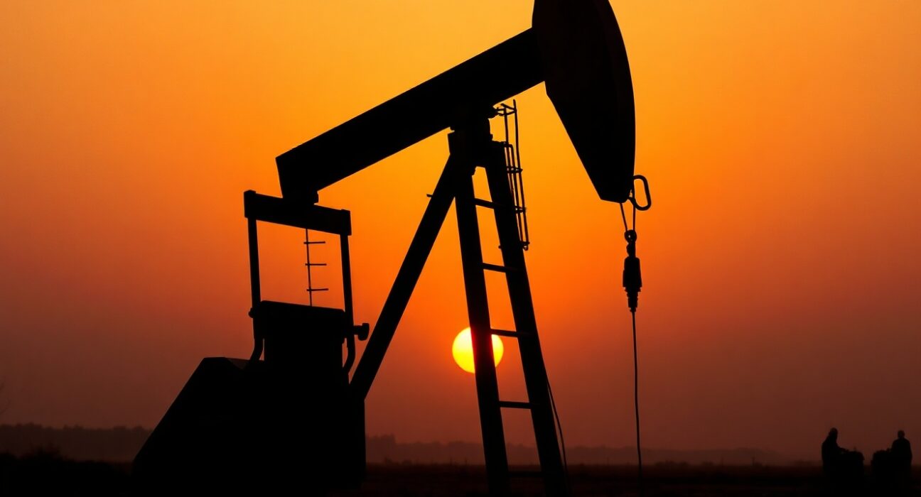 Oil pumpjack silhouette at sunset with smoky horizon representing Middle East tensions