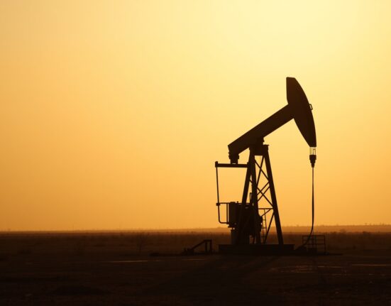 Oil pumpjack silhouetted against a hazy sunset sky, representing cautious crude oil markets amid geopolitical uncertainty.