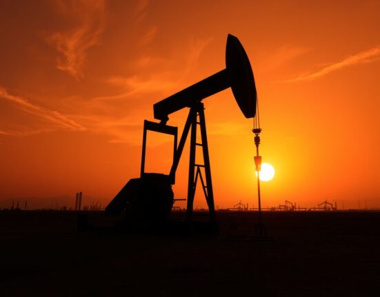 Oil pumpjack silhouetted against a sunset sky, representing WTI crude oil price movements amid economic data and geopolitical tensions.