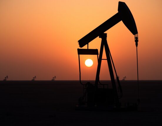 Oil pumpjack silhouetted against sunset sky representing WTI crude oil market retreat