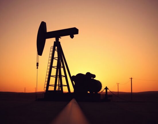 Oil pumpjack silhouette at sunset representing crude oil production and energy markets