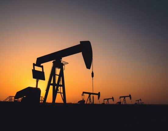 Oil pumpjack silhouetted against sunset over an oil field, representing WTI crude market stability
