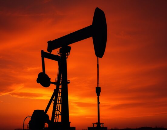 Oil pumpjack silhouetted against a dramatic sunset sky representing geopolitical oil price surge