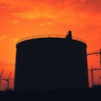 Oil storage tanks at sunset under dramatic sky symbolizing supply fears from Iran tensions