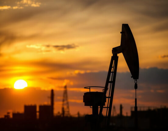 Oil pumpjack silhouetted against sunset, representing rising WTI crude prices amid US-Iran tensions.