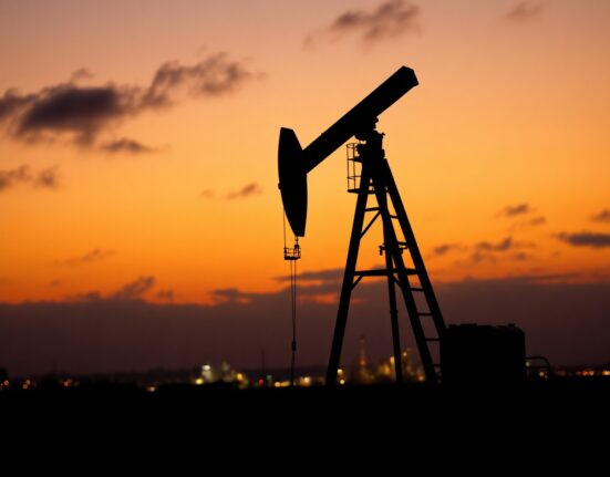 Oil pumpjack silhouetted against sunset sky, representing WTI crude price stability amid geopolitical risks.