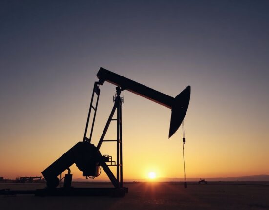 Oil pumpjack silhouette at sunset in an open field