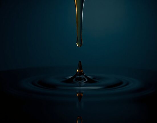 Close-up of a dark oil drop falling onto a reflective surface, representing the sharp decline in WTI crude oil prices.