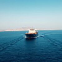 Oil tanker sailing through the Strait of Hormuz under a clear sky.