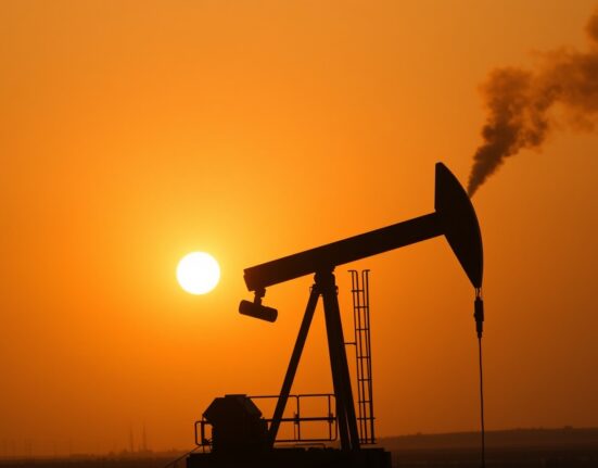Oil pumpjack silhouette against sunset sky with distant smoke, representing Middle East geopolitical supply risks affecting WTI crude oil prices.