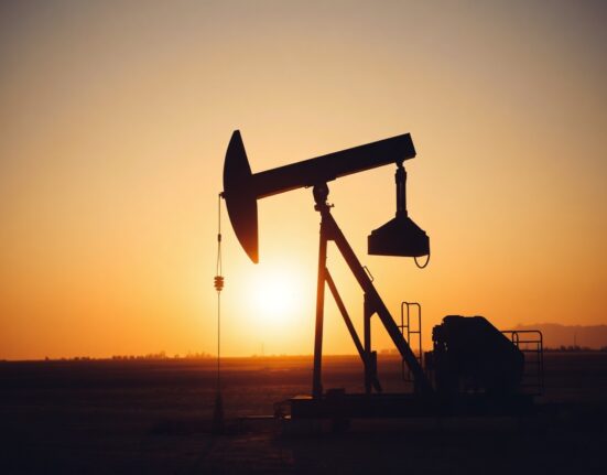 Crude oil pumpjack silhouetted at sunset in an oil field, representing WTI price stagnation amid US-Iran nuclear deadlock.