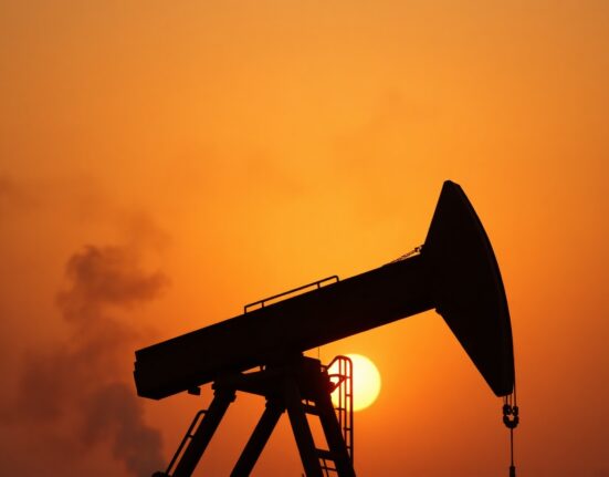 Oil pumpjack silhouette at sunset with hazy horizon suggesting geopolitical tension