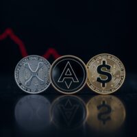XRP, Cardano, and Solana coins on a reflective surface with a downward chart trend