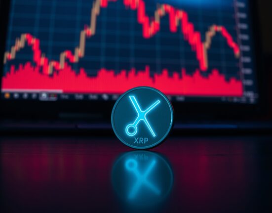 Dimly lit XRP token icon with a red downtrend chart in the background, symbolizing bearish market conditions.